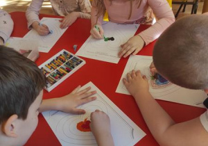Dzieci malują pastelami kolorowe serduszka.